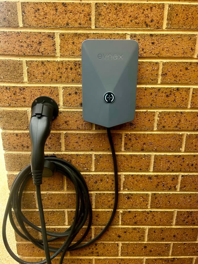 Wall-mounted EV charger installation on brick