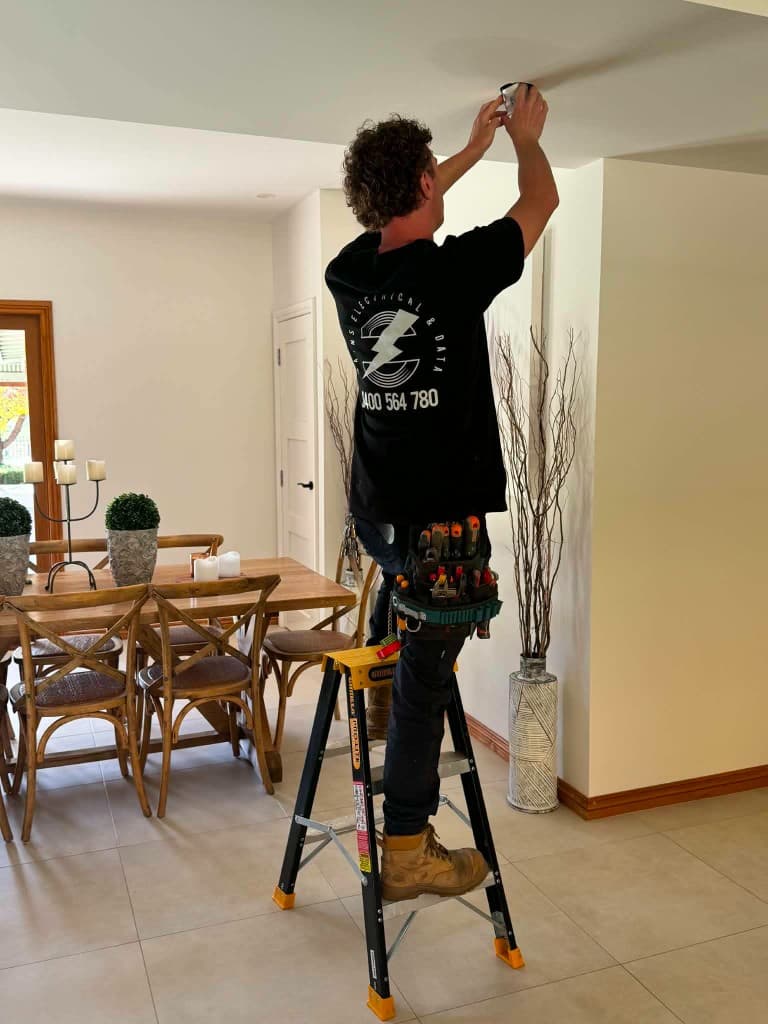 Electrician completing work on a wall-mounted fitting